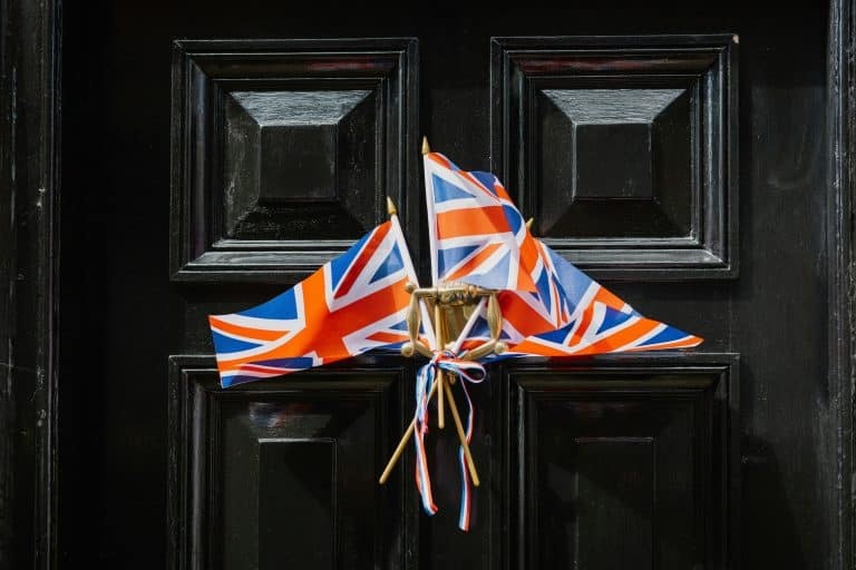 Close-up of a black door decorated with two Union Jack flags tied together, symbolizing the United Kingdom and Brexit.